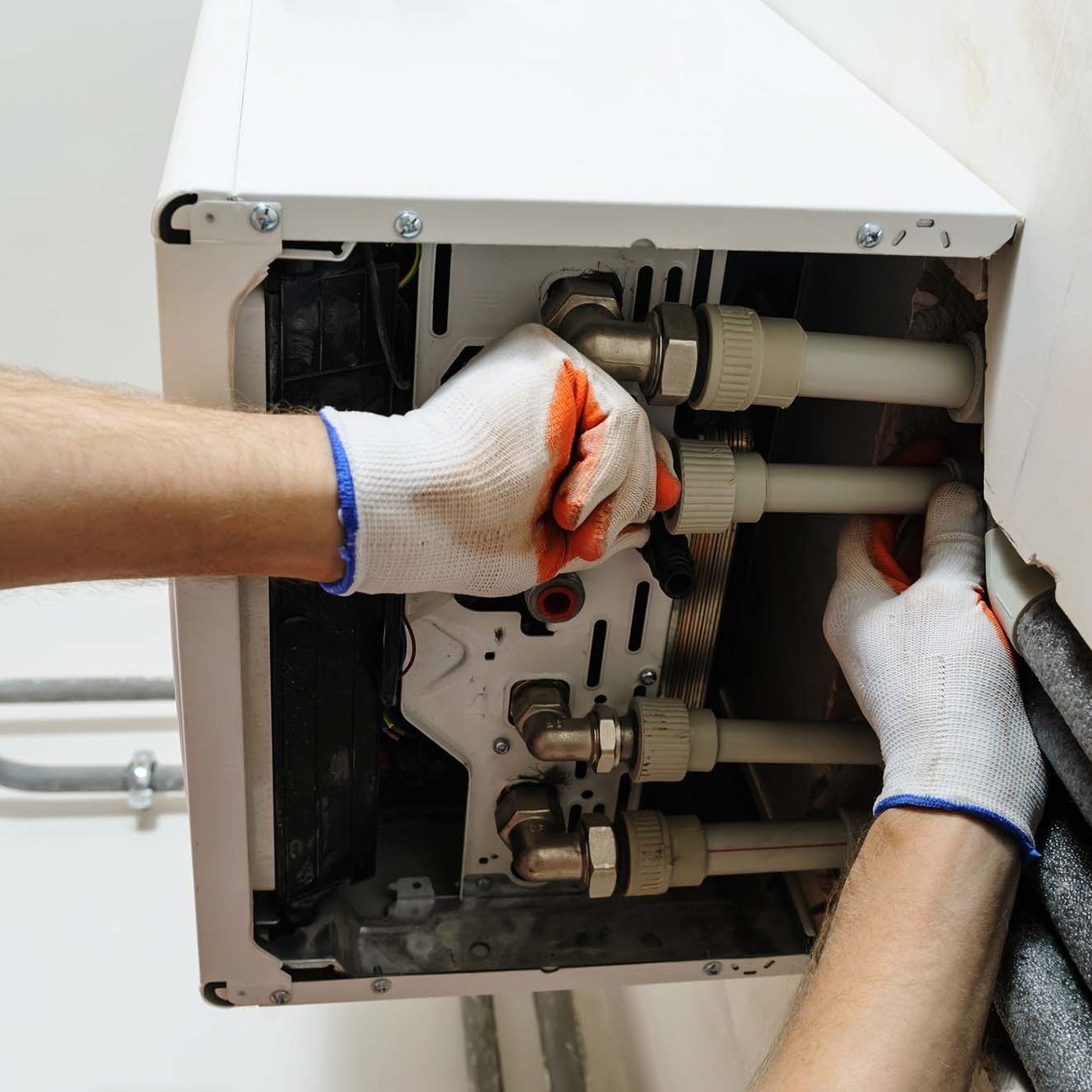 Plumber attaches to pipe gas boiler using adjustable wrench.